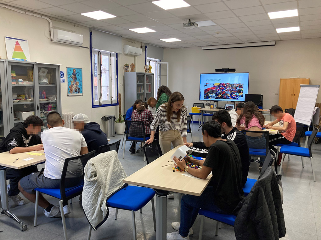 Varios grupos de jóvenes en una biblioteca, juegan con piezas de lego