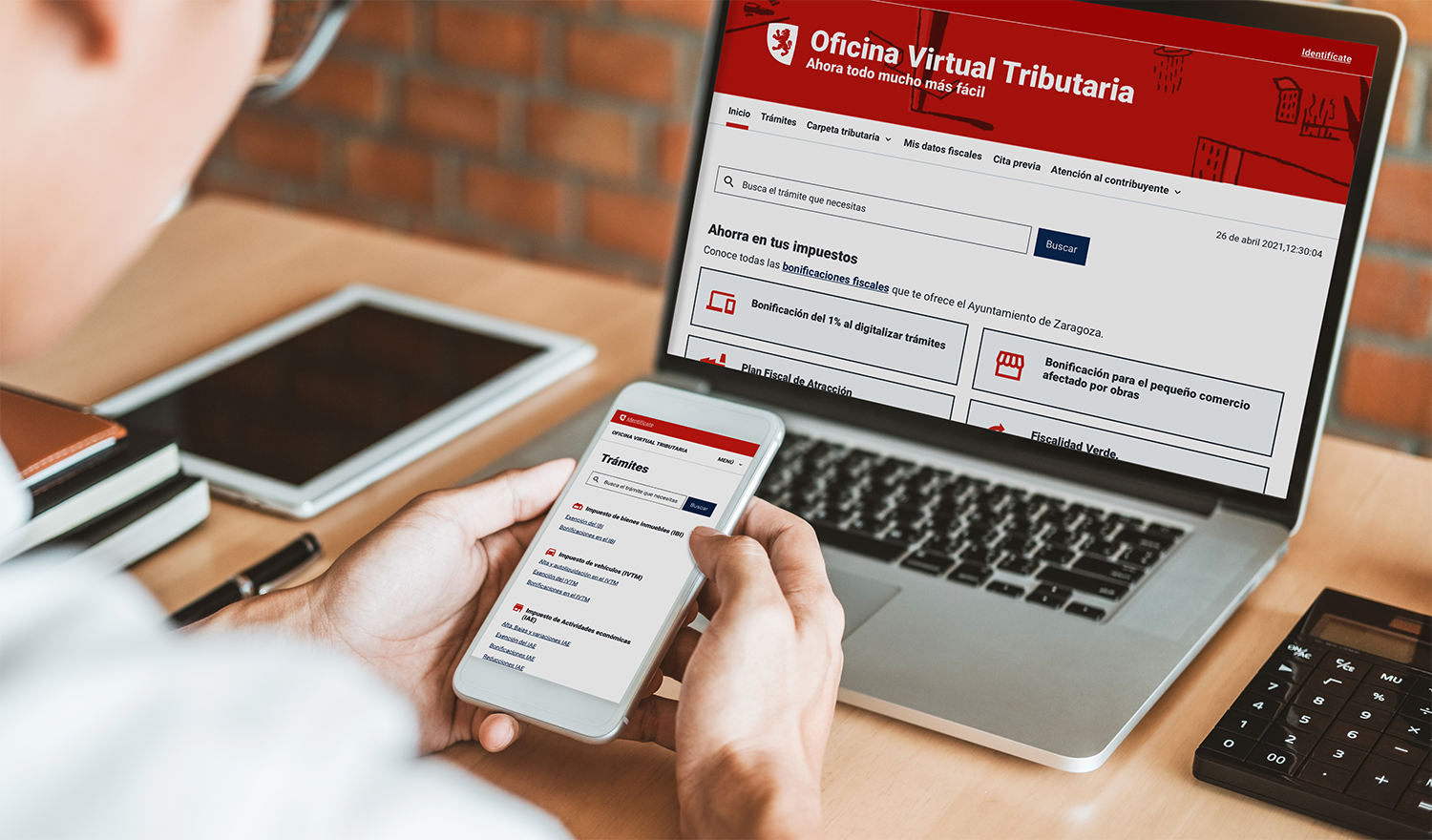 Una persona usando en su móvil y ordenador la Oficina virtual Tributaria