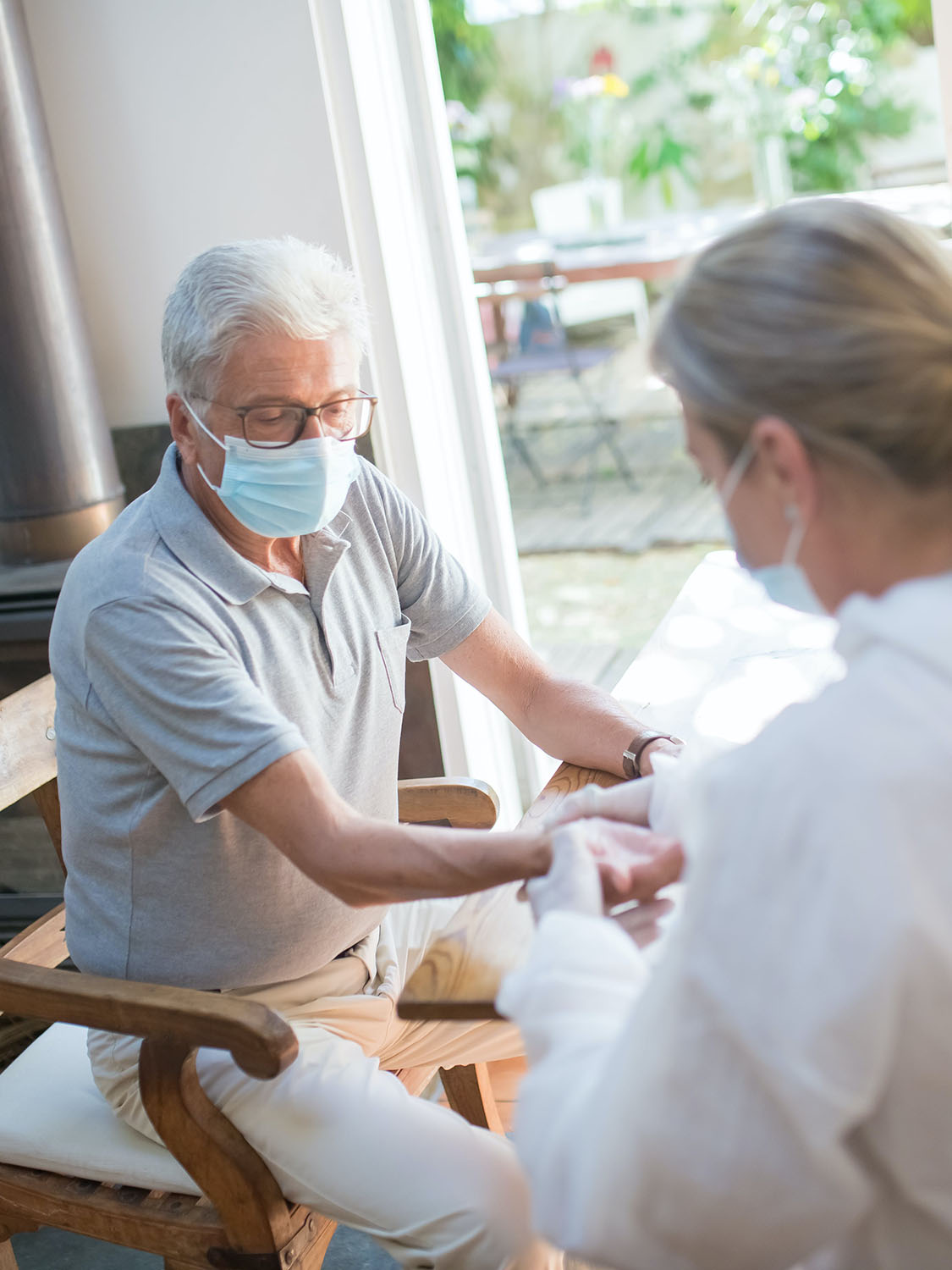 Una sanitaria inyecta en el brazo a un hombre con el pelo blanco y mascarilla