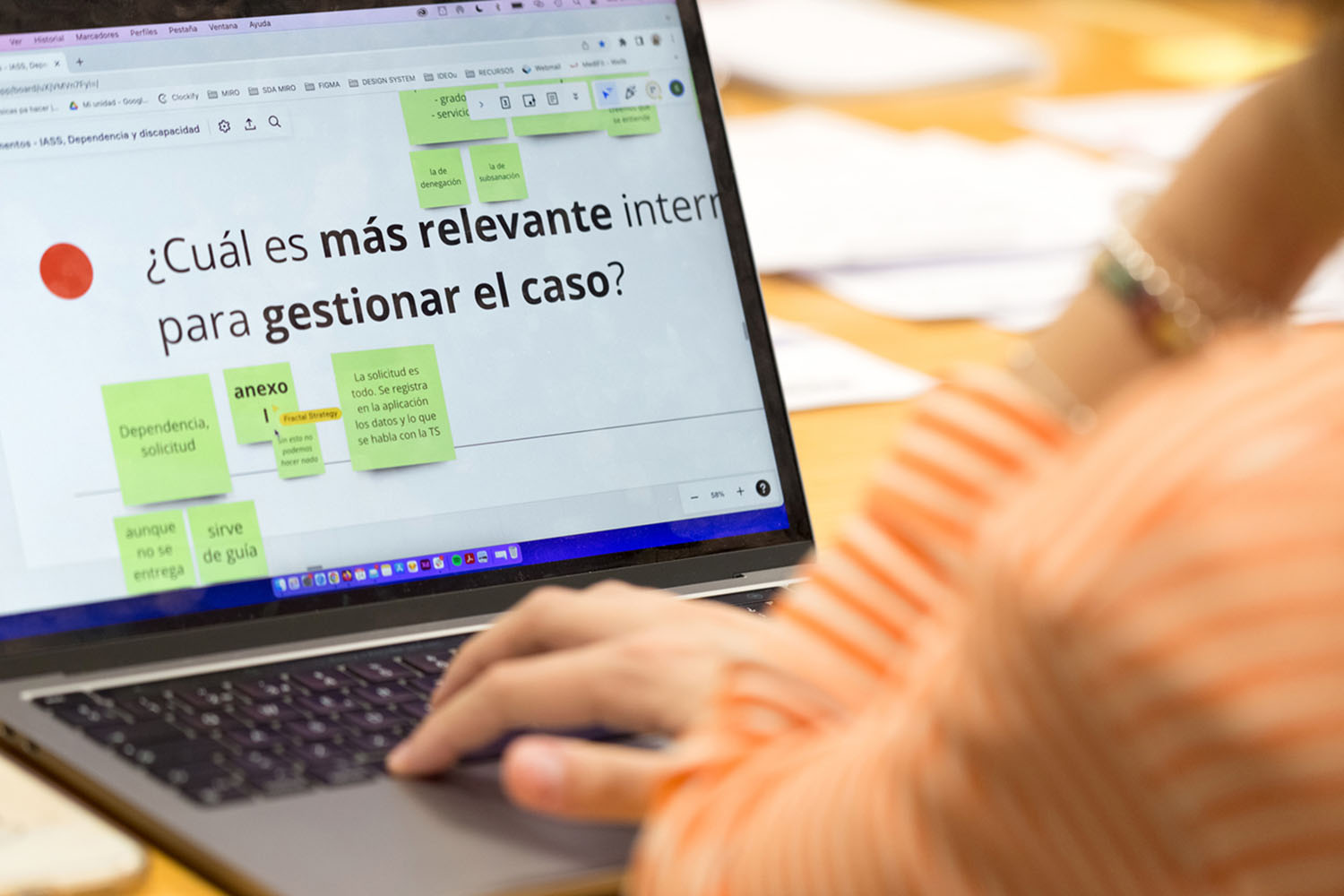 Una persona teclea en un ordenador. En la pantalla digital se ve una pizarra digital con muchos post its y en uno de ellos se lee ¿Cuál es más relevante para gestionar el caso?